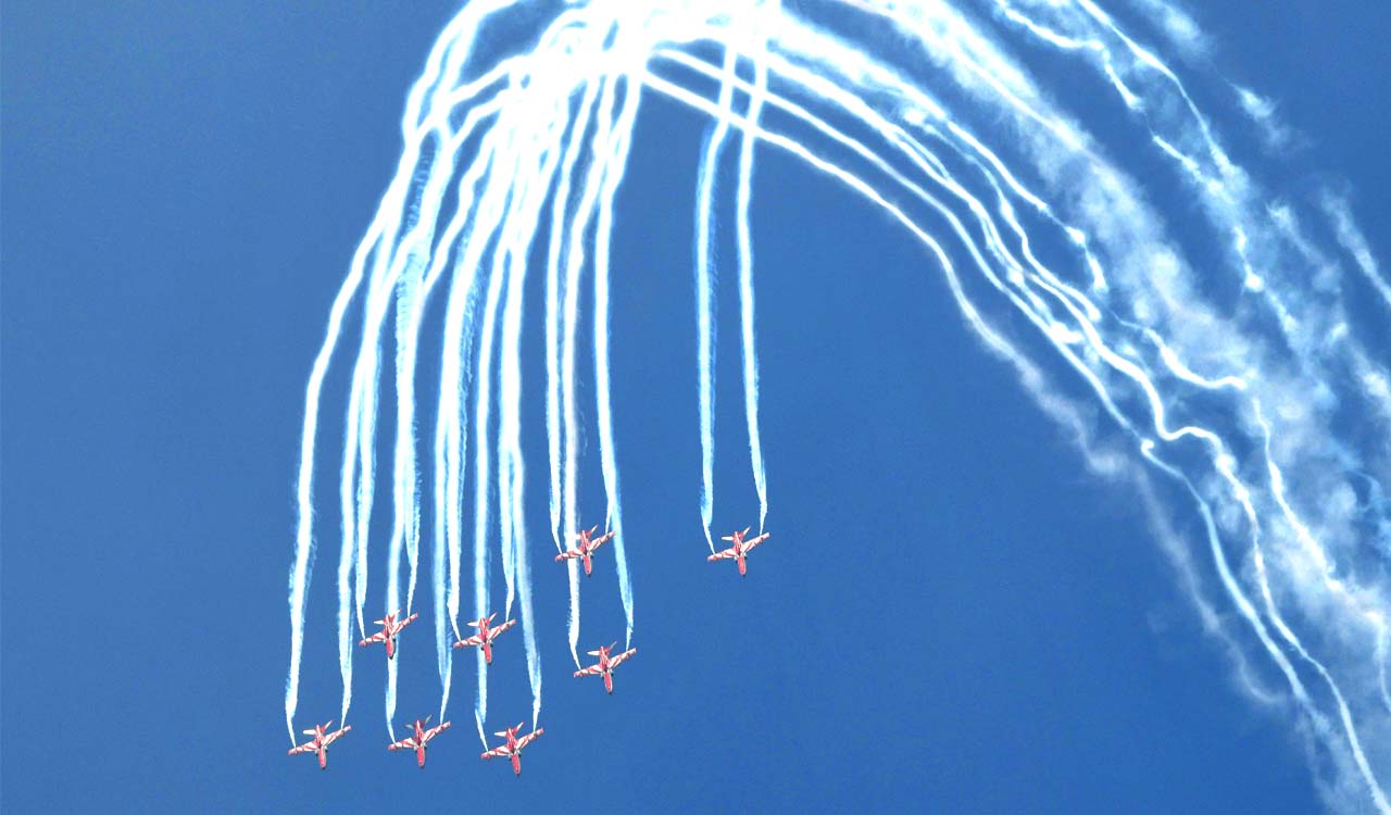Suryakiran jets drawing white smoke loops during an aerobatic display